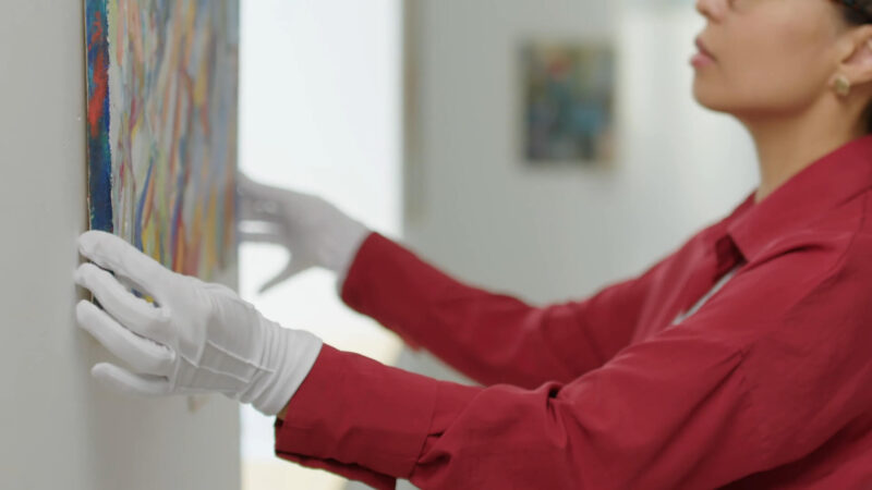 A woman hanging an artwork/picture on the wall