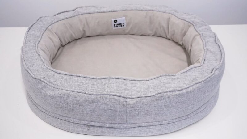 A soft, gray donut-shaped pet bed with a cushioned interior for comfort