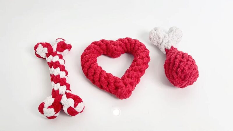 Three braided cotton rope dog toys shaped like a bone, heart, and drumstick in red and white