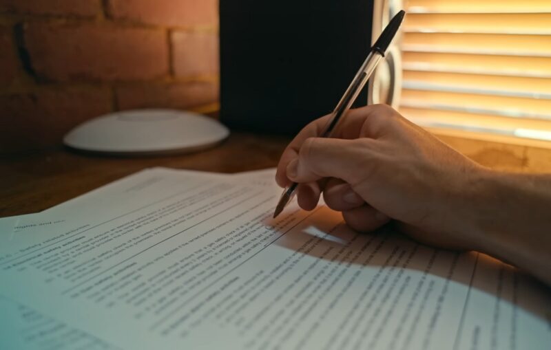 A close-up of a business translator’s hand signing an official document, finalizing a professional translation contract