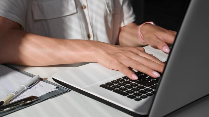  A translator typing on a laptop, surrounded by office documents and notes, working on a translation project